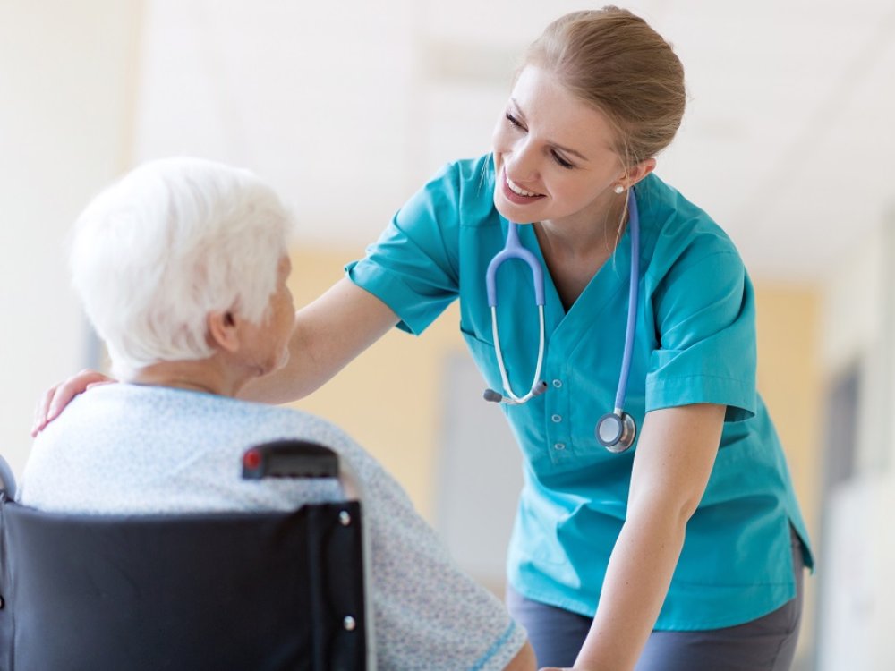 Senior woman in wheelchair with nurse in hospital